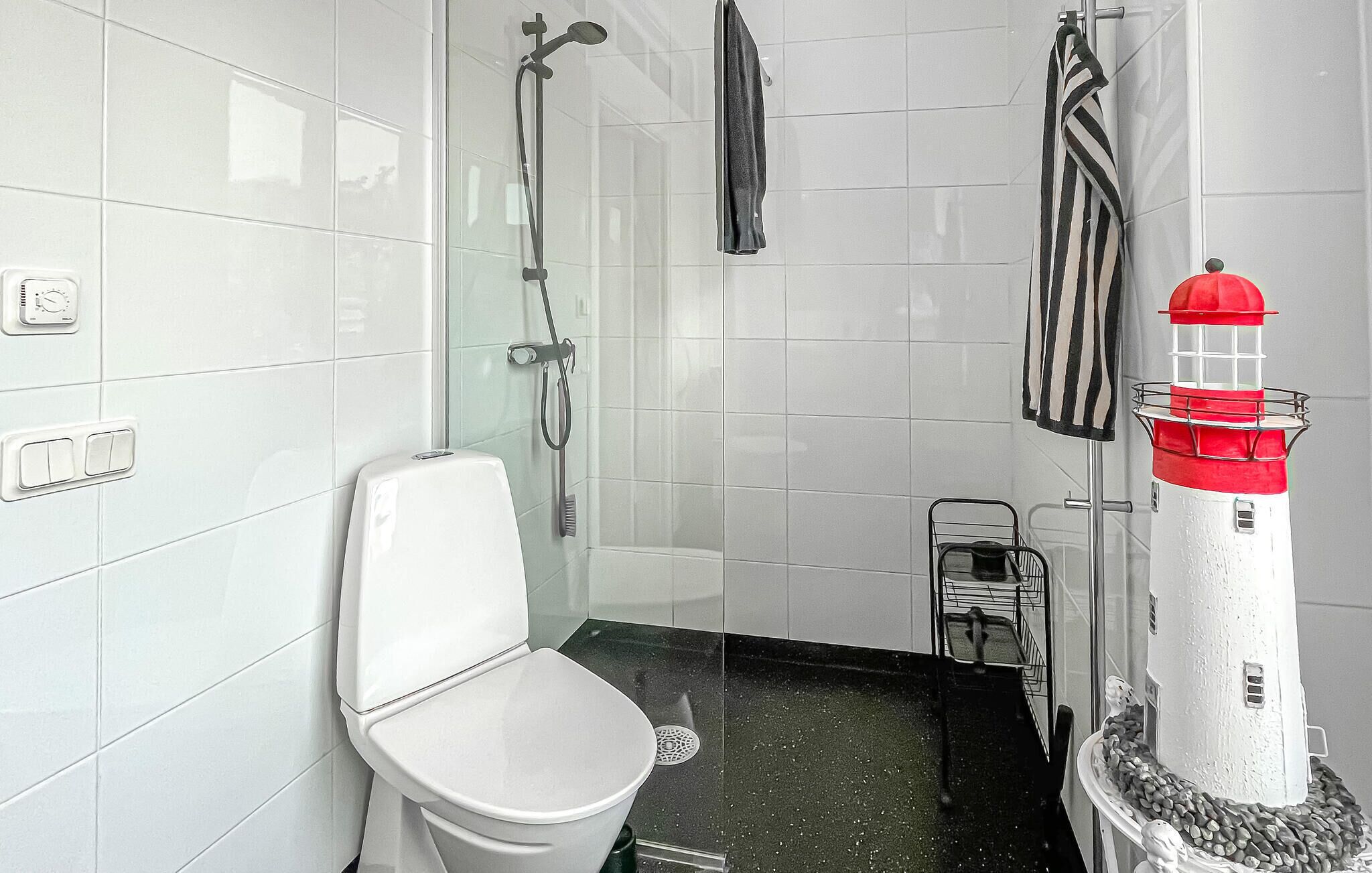 Une salle de bain équipée de toilettes, d’une douche, d’un porte-serviettes et d’un phare décoratif.
