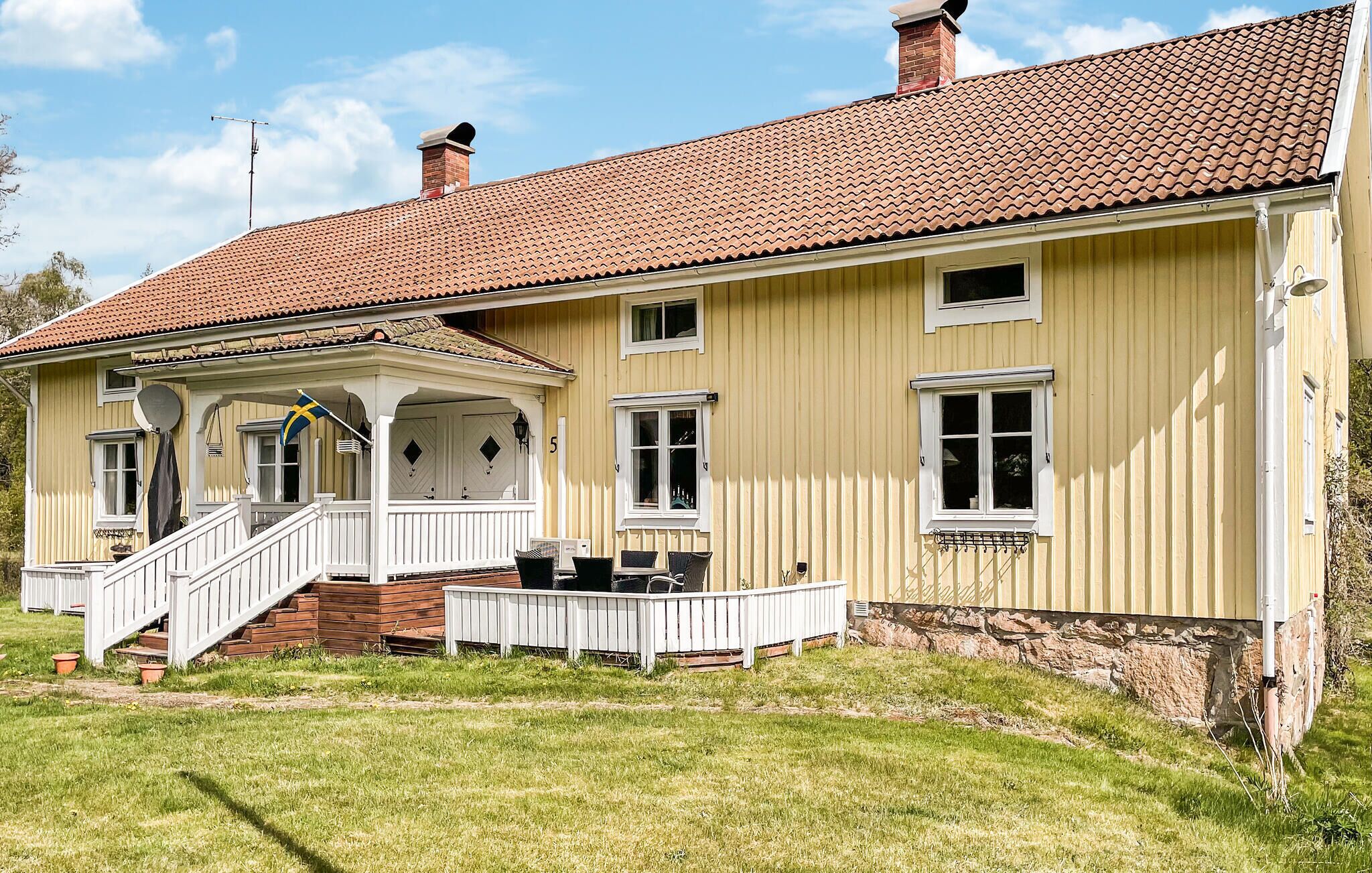 Une maison à deux étages avec un porche, une cheminée et un drapeau.