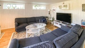 A living room with a sectional sofa, a coffee table, a TV, and a cabinet.