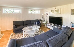 A living room with a sectional sofa, a coffee table, a TV, and a cabinet.