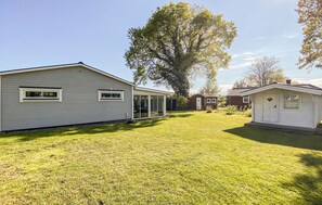 A residential property with a large lawn, a detached garage, and a house with a covered patio.