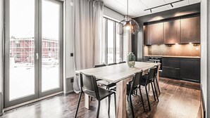 A modern kitchen with dark cabinets, a wooden dining table, and a large window. - Cozy home in Järbo with sauna (Järbo)