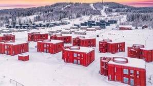 A snowy landscape with red buildings, a ski slope, and a forested hill in the background. - Cozy home in Järbo with sauna (Järbo)