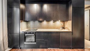 A modern kitchen with dark cabinetry, a built-in oven, and a sink. - Cozy home in Järbo with sauna (Järbo)