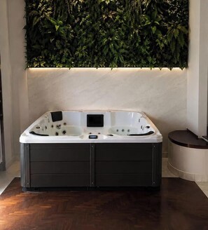 A modern bathroom with a large, dark-colored bathtub, a wall-mounted plant wall, and a wooden floor. - Dreamora Charme & Relax Salerno (Salerno)