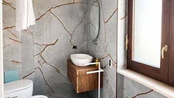 A bathroom with a white bathtub, a wooden vanity, and a large mirror.
