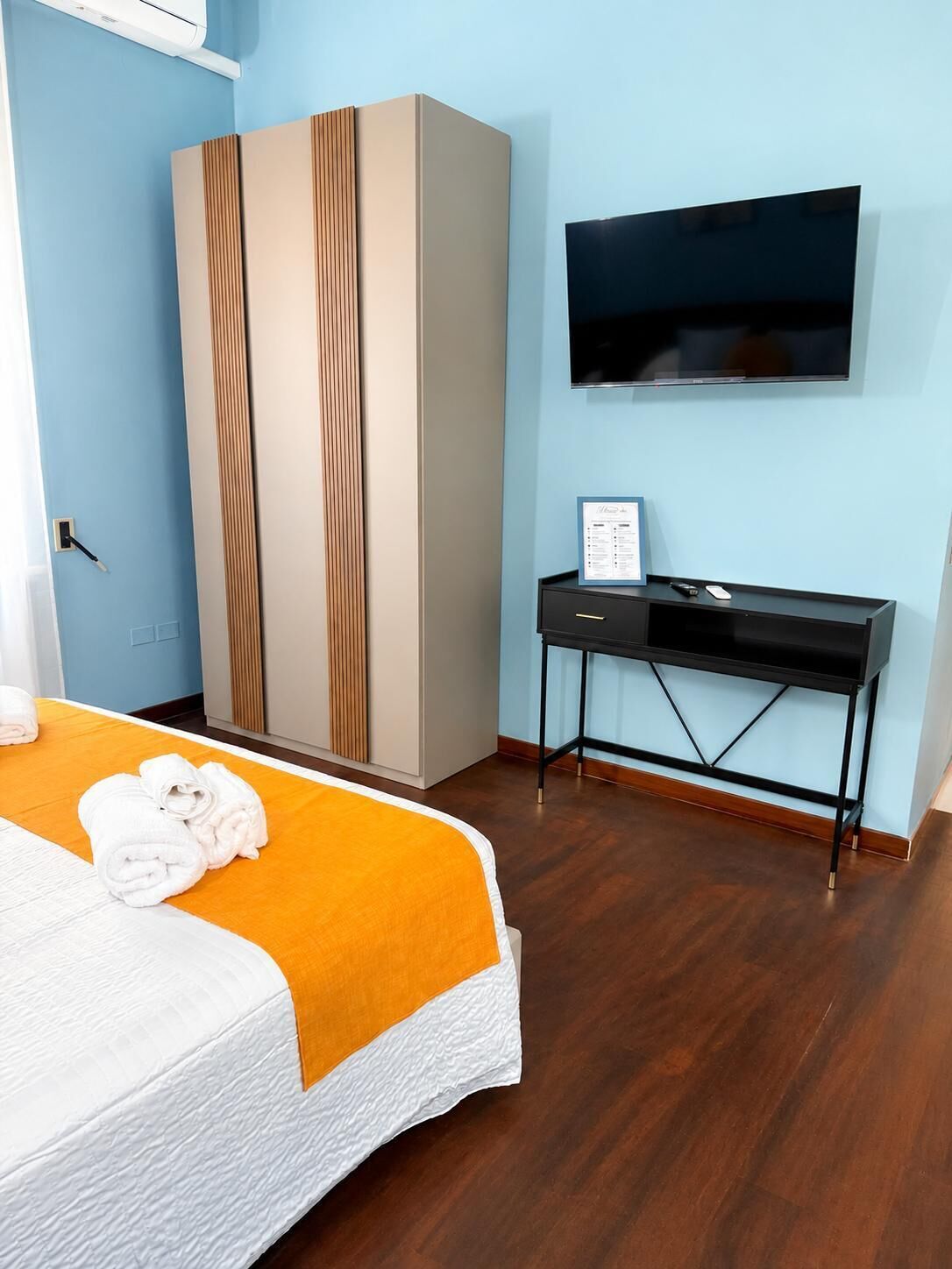 Una camera d'albergo con un letto, un armadio, una scrivania e una televisione.