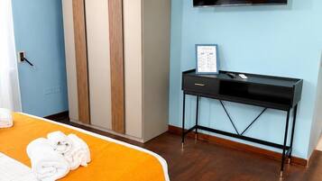 Una camera d'albergo con un letto, un armadio, una scrivania e una televisione.