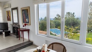 Une pièce dotée d’une télévision, d’une cheminée, d’une table à manger et offrant une vue sur une piscine.