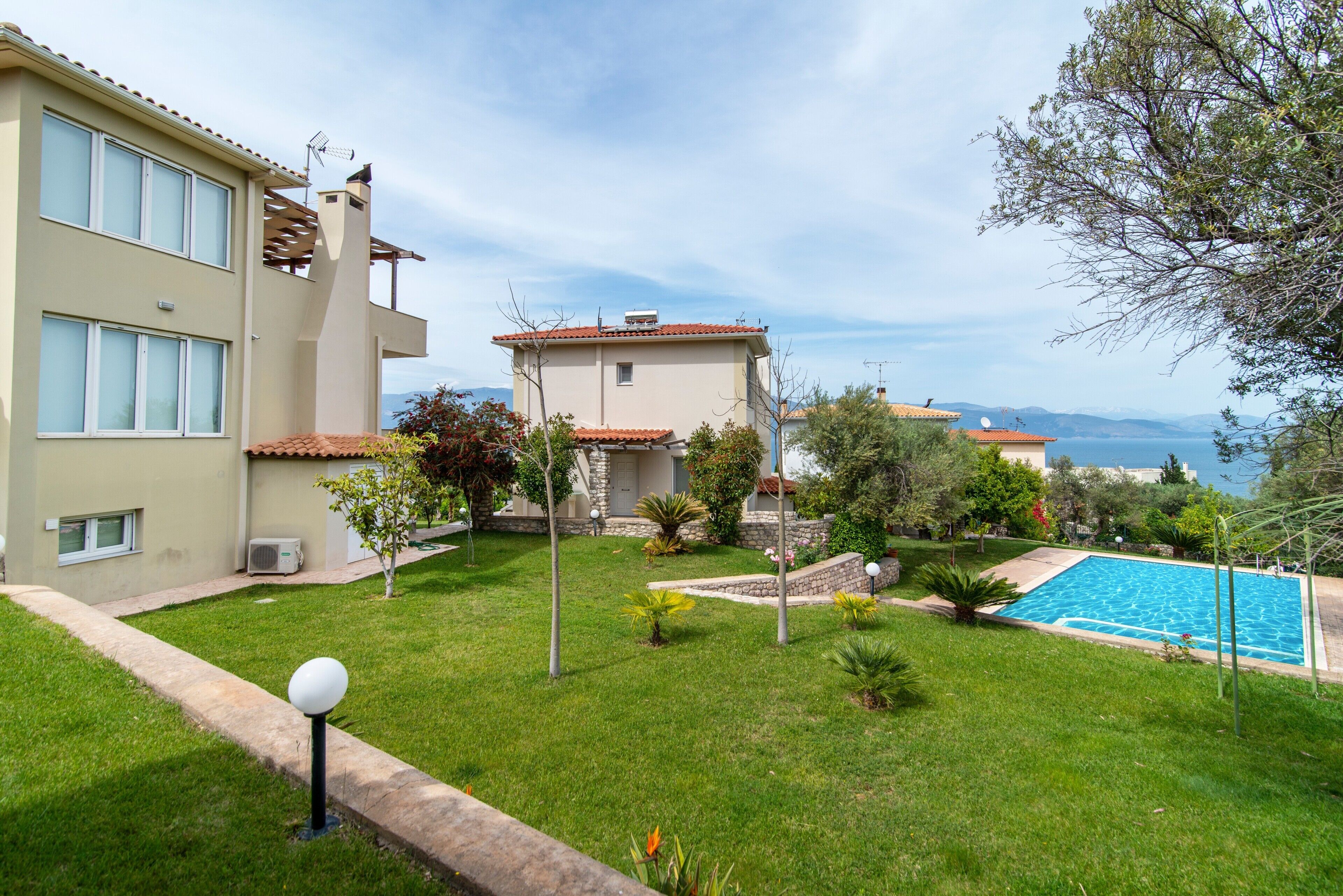 Une propriété résidentielle dotée d’une piscine, d’une pelouse bien entretenue et offrant une vue sur la mer.