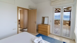 Une chambre avec un lit, une commode, un miroir et une vue sur l’extérieur, visible à travers les portes coulissantes.