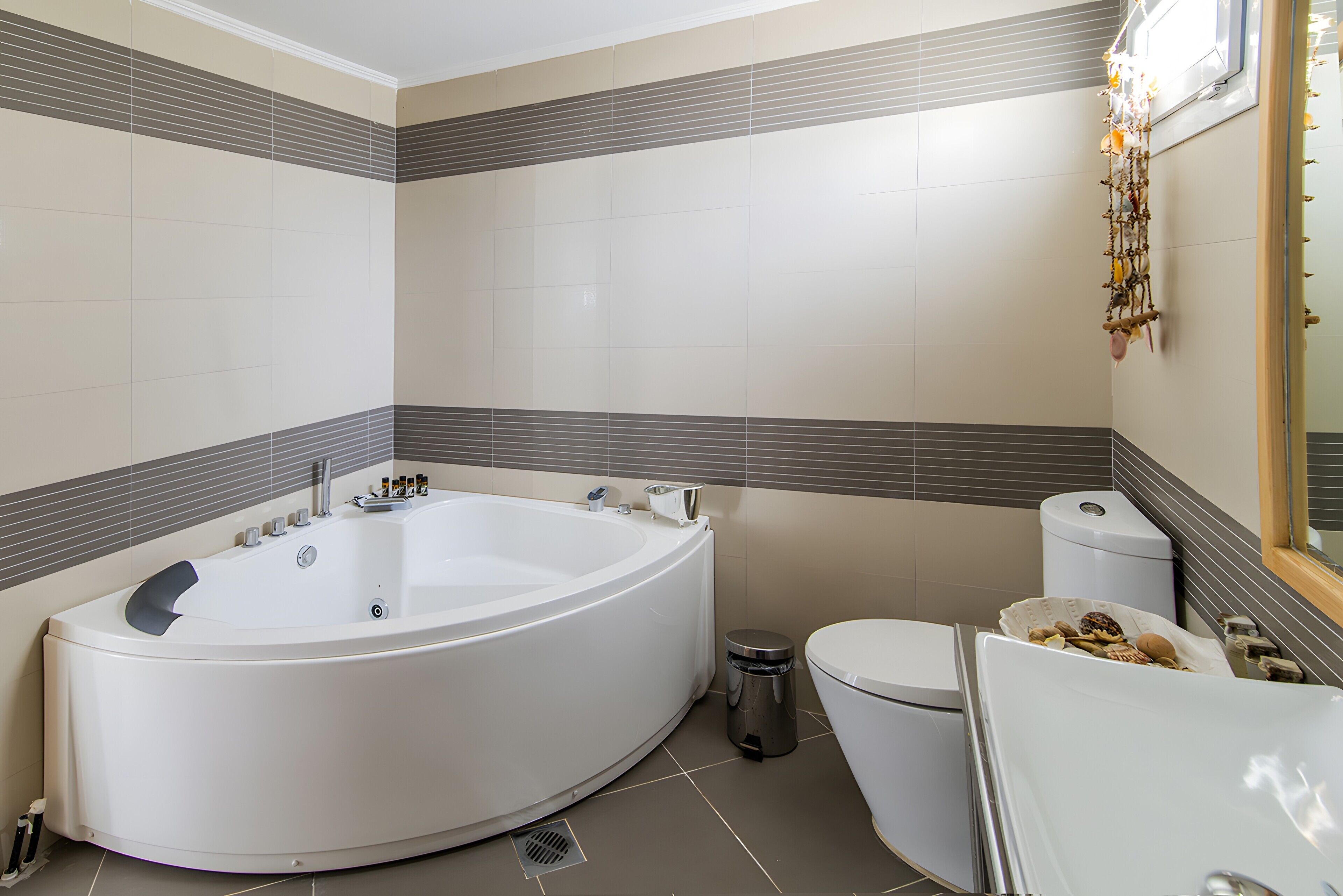 Et moderne badeværelse med et fristående badekar, toilet og skraldespand.