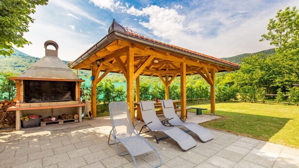 An outdoor barbecue area with a grill, lounge chairs, and a wooden pavilion. - 3 bedroom beautiful home in Jasenak (Jasenak)