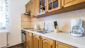 A kitchen with wooden cabinets, a stainless steel sink, a Bosch coffee maker, and a window with a leaf-patterned curtain. - 3 bedroom beautiful home in Jasenak (Jasenak)