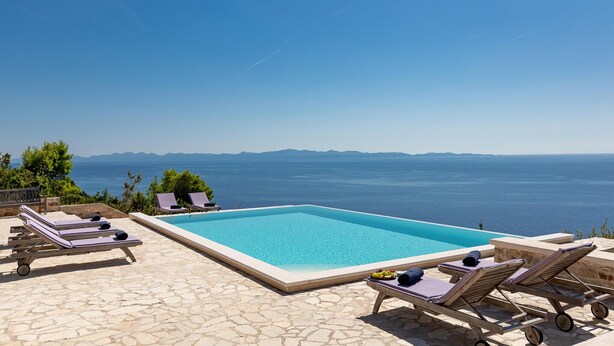 Ein Pool mit Liegestühlen und Meerblick.