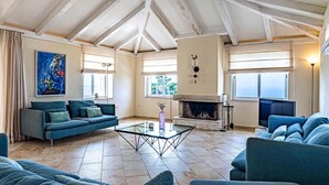 Ein großzügiges Wohnzimmer mit hoher Decke, Kamin und großem Fenster.
