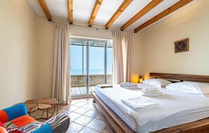 A hotel room with a bed, a table, a chair, and a view of the sea through a glass door. - Luxurious home in Potomje (Potomje)