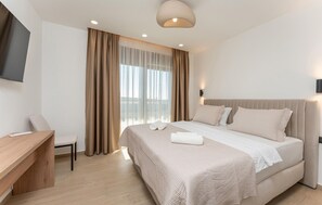 Ein modernes Hotelzimmer mit Bett, Schreibtisch und Fernseher.