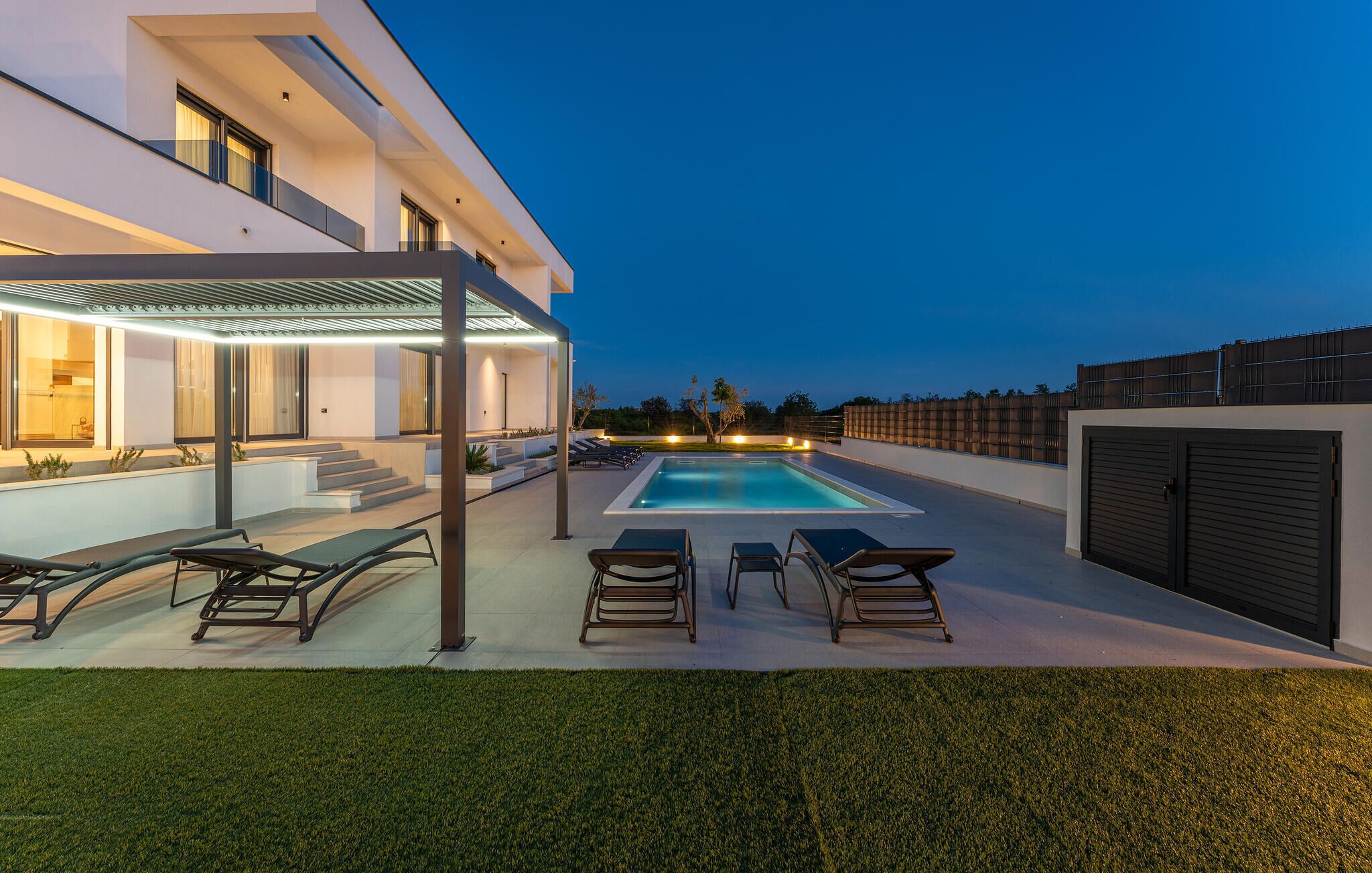 A modern outdoor pool area with lounge chairs and a covered seating area.