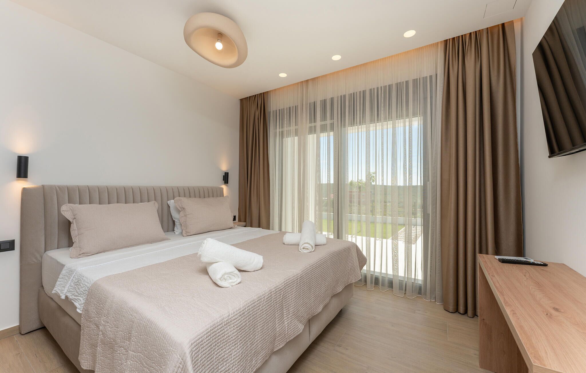 Ein modernes Hotelzimmer mit einem großen Bett, einem Schreibtisch und einem Fernseher.