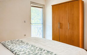 A bedroom with a bed, a wooden wardrobe, a window with a view of a balcony, and a door. - Awesome apartment in Medulin with WiFi (Medulin)