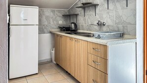 A compact kitchen with a white refrigerator, wooden cabinets, a sink, and a countertop with a kettle and a basket. - Awesome apartment in Medulin with WiFi (Medulin)