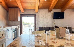 A kitchen with wooden beams, a dining area with a table set for two, and a TV mounted on the wall. - Awesome apartment in Umag with WiFi (Umag)