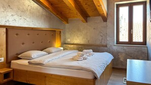 Un dormitorio con cama de madera, cabecero, mesita de noche, ventana con vistas y techo de madera.