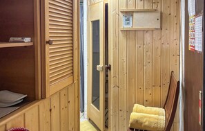 Een houten interieur met een schuifdeur, een handdoek op een stoel en een plank met een apparaat.