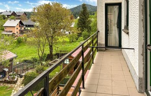 Een balkon met uitzicht op een groen landschap en huizen.