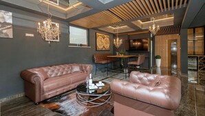 Een modern interieur met leren banken, een ronde salontafel, kroonluchters en een groot raam.