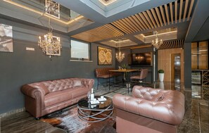 Ein modernes Interieur mit Ledersofas, einem runden Couchtisch, Kronleuchtern und einem großen Fenster.