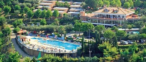 An aerial view of a residential area with a swimming pool surrounded by houses and greenery.