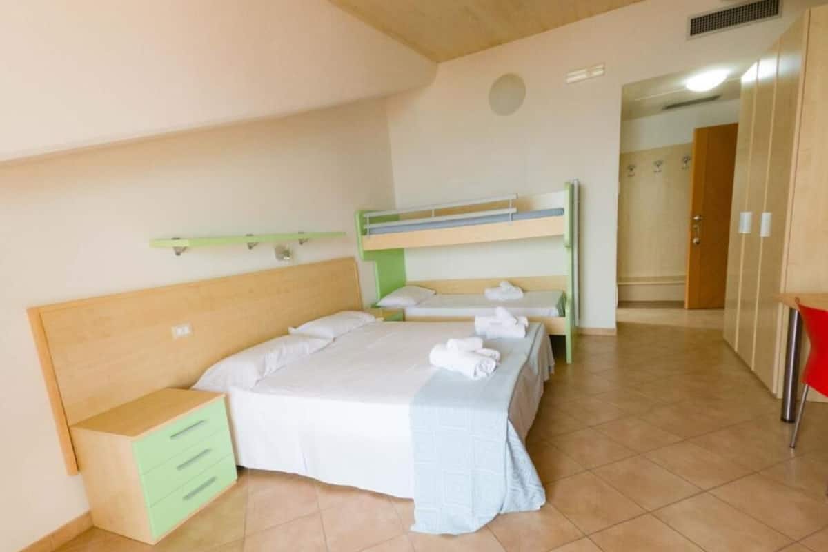 A bedroom with a bunk bed, a single bed, a nightstand, and a wardrobe.