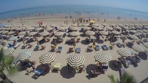 Ein Strand mit vielen Sonnenschirmen und Liegestühlen.