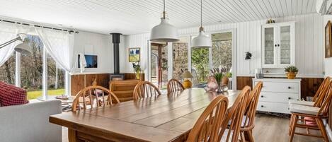 Un vaste espace dédié à la salle à manger, avec une table et des chaises en bois, un canapé et une grande fenêtre donnant sur l’extérieur.