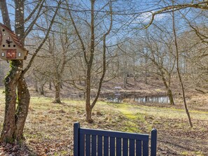 A bench in a wooded area with a birdhouse on a tree. - 6 Person Holiday Home in Farso (Farso)