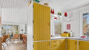 Una cocina moderna con armarios amarillos, un ventanal con vistas y un comedor con sillas de madera.
