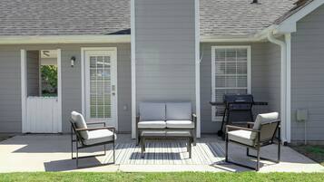 A patio with two chairs, a bench, and a grill.