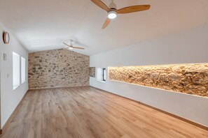 A room with a sloped ceiling, wooden flooring, stone wall accents, and a built-in shelf.