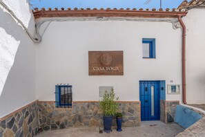 A building with a sign reading 'CASA YOGA,' stone walls, a blue door, and a blue window.