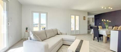 Un salon moderne comprenant un canapé, une table basse et un coin repas avec des chaises et une table.