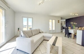 Ein modernes Wohnzimmer mit einer Couch, einem Couchtisch und einem Essbereich mit Stühlen und einem Tisch.