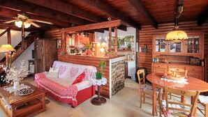 Ein gemütliches Blockhaus-Interieur mit einer Couch, einem Esstisch, Holzschränken und einer Küchenzeile.