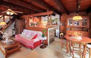 Ein gemütliches Blockhaus-Interieur mit einer Couch, einem Esstisch, Holzschränken und einer Küchenzeile.