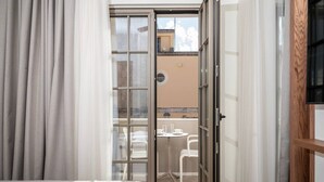 A hotel room with a bed, a glass door leading to an outdoor seating area, and a television on the wall. - Volaka Luxury Suites `Ruby` (Kos)