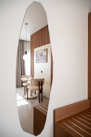A modern interior with a dining area, a large mirror, and a wooden headboard.