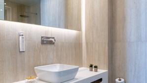 A modern bathroom with a large mirror, a white vessel sink, a handheld showerhead, and a toilet paper holder. - Volaka Luxury Suites `Ruby` (Kos)