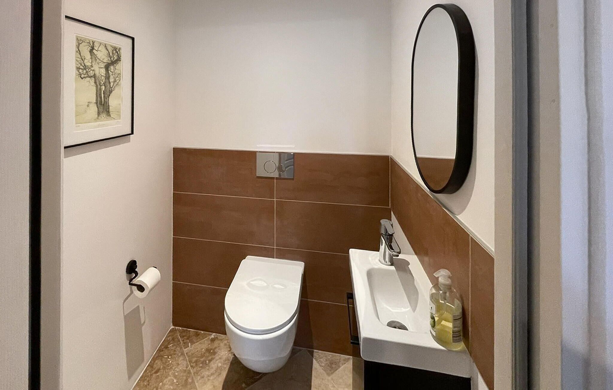 A bathroom with a toilet, sink, and mirror.
