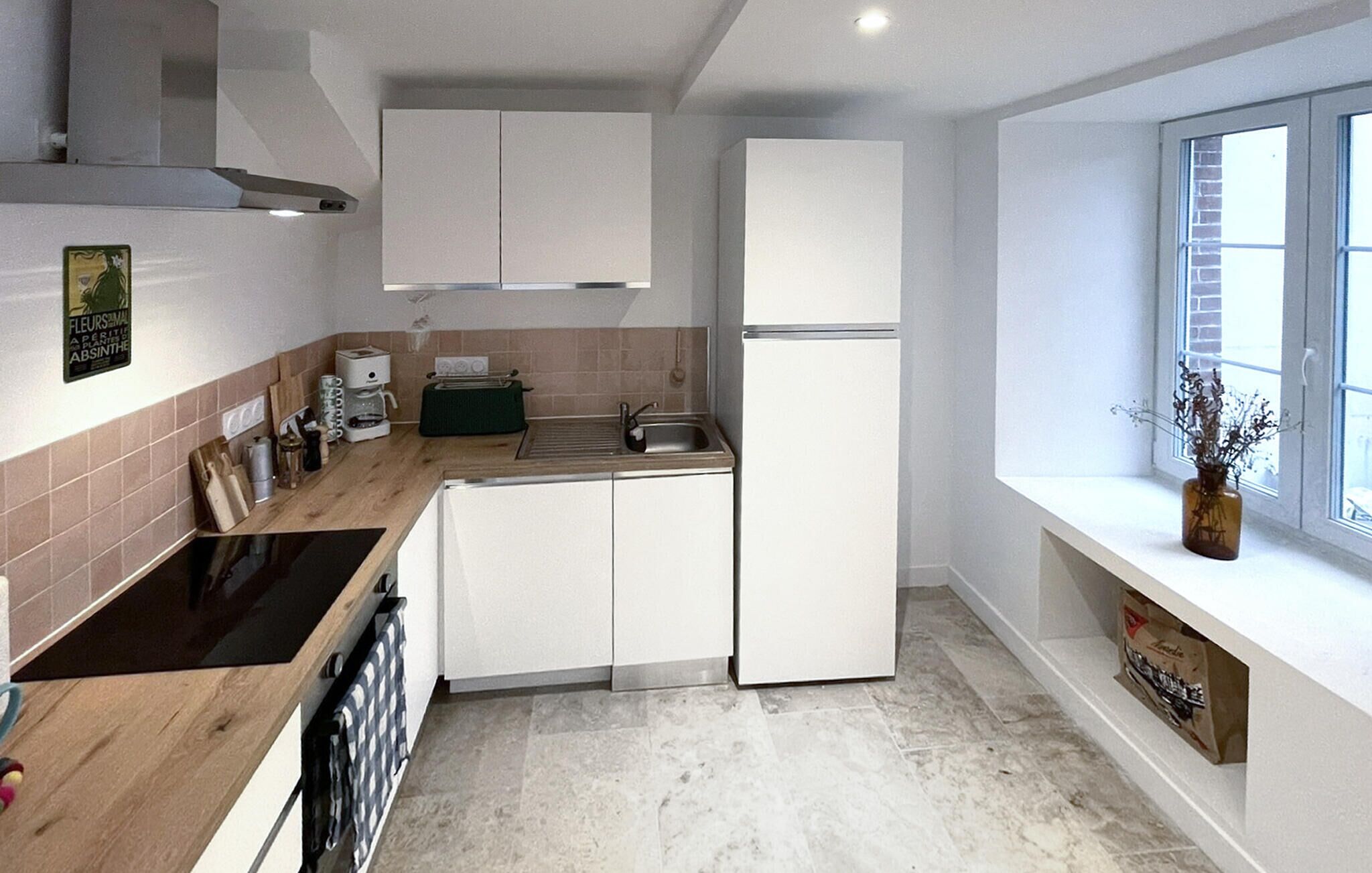 Een moderne keuken met witte kasten, een inbouwoven, een spoelbak en een raam met uitzicht.